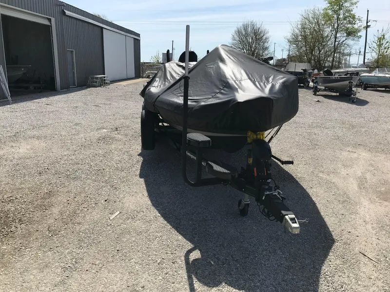 Slide: The Image of 2025 Lund 1875 Impact XS Sport boat covered on a trailer in a gravel lot. - 4