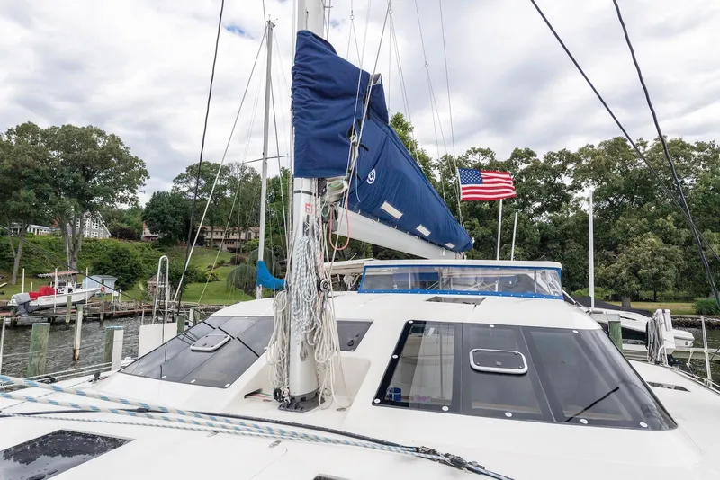 Slide: The Image of Sailing catamaran Balance 451, 2017 model, docked with American flag, lush greenery in background. - 10