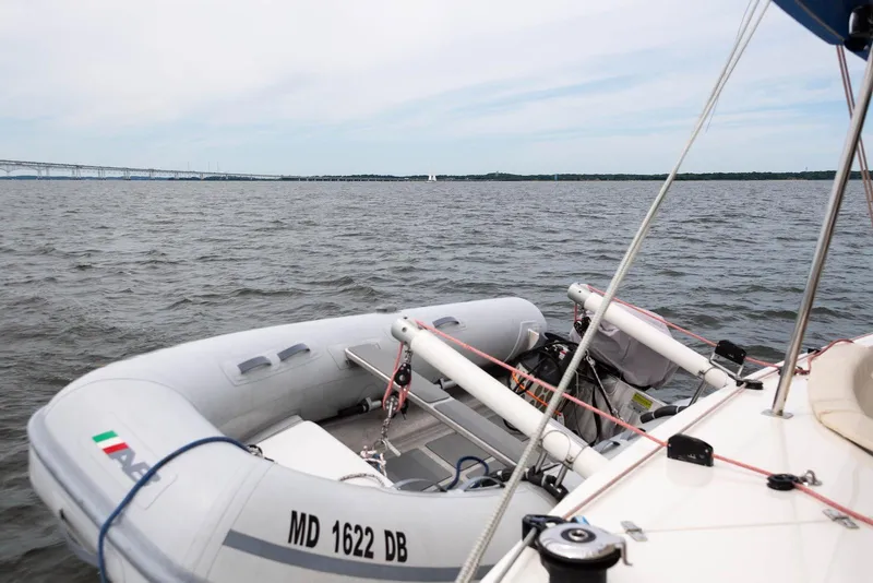 Slide: The Image of Inflatable boat on water near sailboat, Balance 451, 2017 model, with distant bridge view. - 5