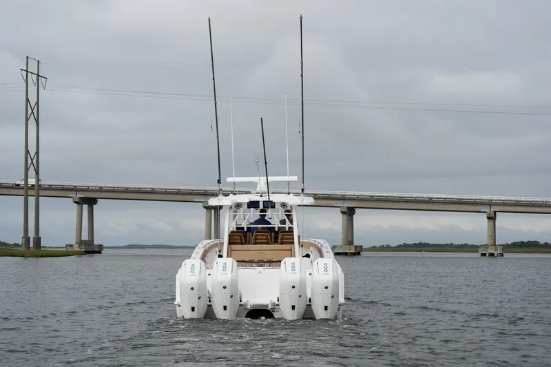 Slide: The Image of 2025 Caymas 44 CT boat with multiple engines on a calm waterway near a bridge. - 0