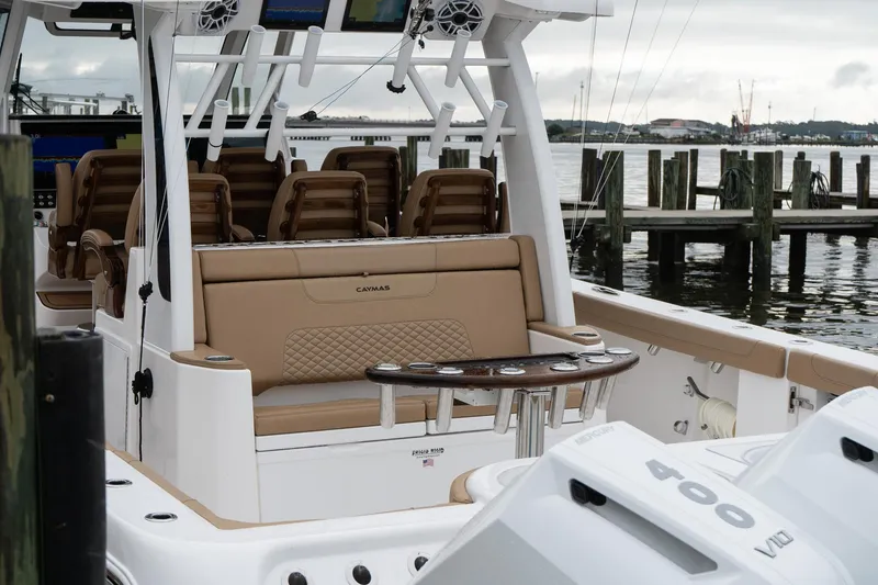 Slide: The Image of 2025 Caymas 44 CT boat interior with seating and fishing rod holders at a dock. - 17