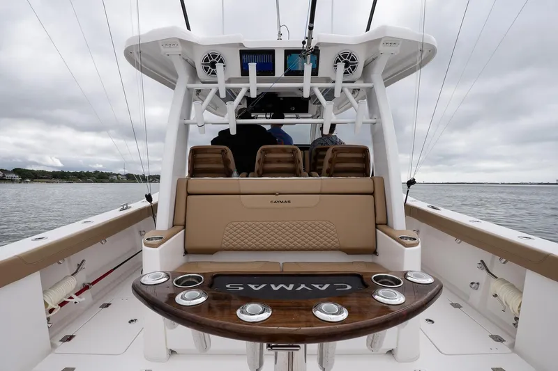 Slide: The Image of 2025 Caymas 44 CT boat interior with seating and fishing rod holders on a cloudy day. - 22