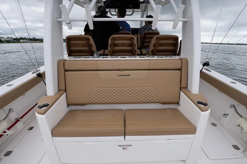 Slide: The Image of 2025 Caymas 44 CT boat interior with tan seating and cup holders on a calm water backdrop. - 26
