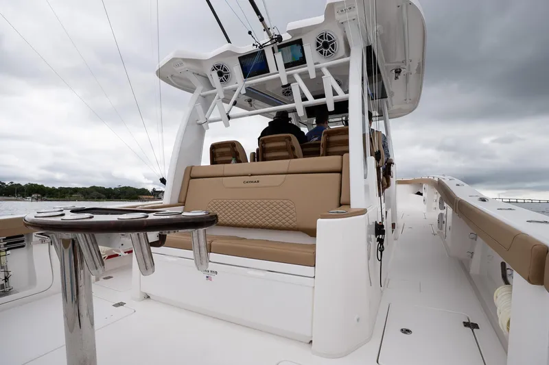 Slide: The Image of 2025 Caymas 44 CT boat interior with seating and helm, under cloudy skies. - 27