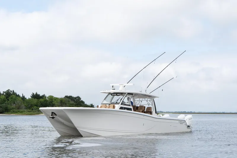 Slide: The Image of 2025 Caymas 44 CT boat on calm water with fishing rods, cloudy sky background. - 3
