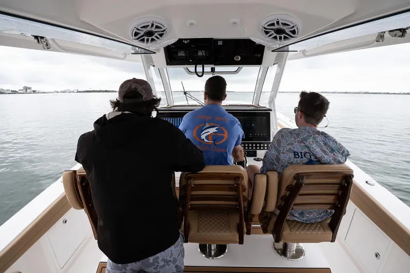 Slide: The Image of Three people navigating a 2025 Caymas 44 CT boat on calm waters. - 30