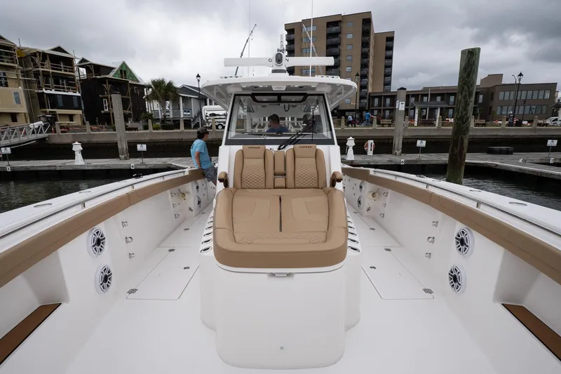 Slide: The Image of 2025 Caymas 44 CT boat with tan seating, docked at a marina under cloudy skies. - 32