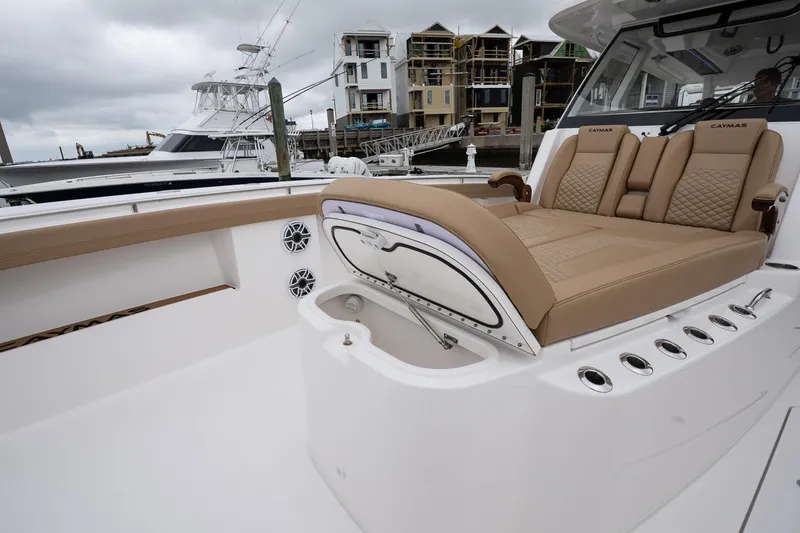 Slide: The Image of 2025 Caymas 44 CT boat interior with tan seating, docked near waterfront homes. - 34