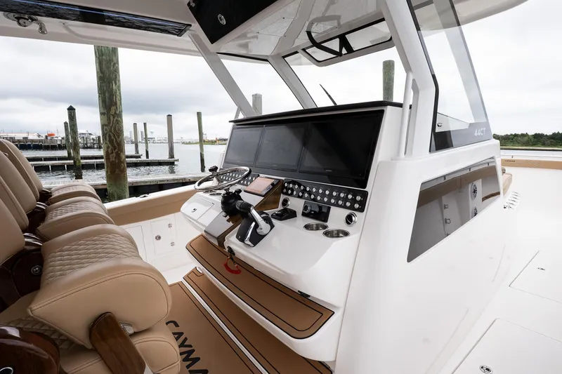 Slide: The Image of 2025 Caymas 44 CT boat cockpit with modern controls and luxurious seating at a marina. - 38