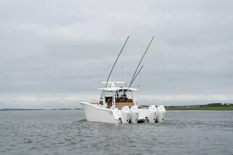 Slide: The Image of 2025 Caymas 44 CT boat with multiple outboard engines on a calm waterway. - 9