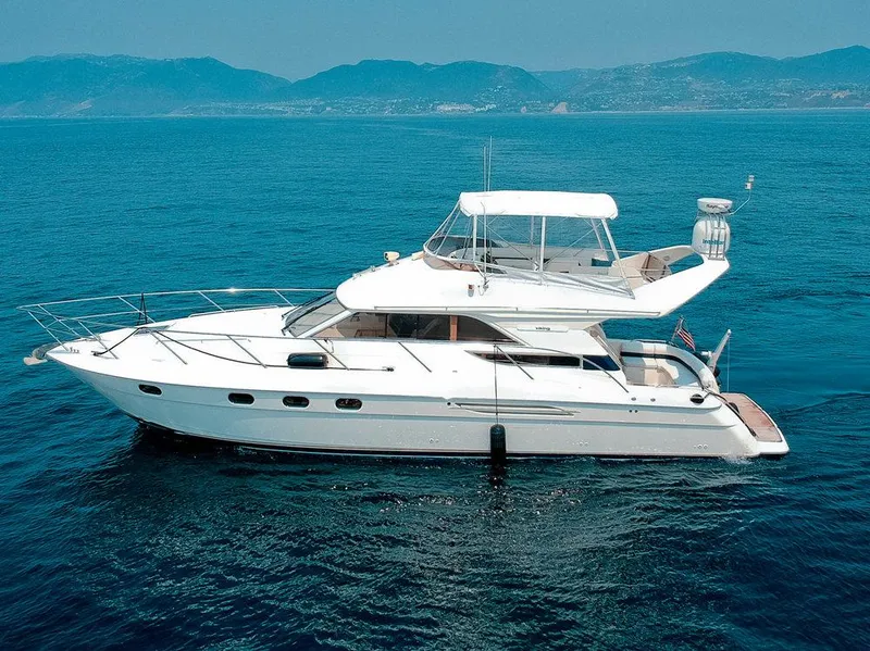 The Image of 2000 Viking 46 Flybridge Sport Cruiser on open sea with mountainous backdrop. - 1