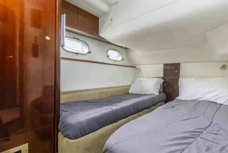 Slide: The Image of Twin beds in a 2000 Viking 46 Flybridge Sport Cruiser cabin, featuring wood paneling and portholes. - 30