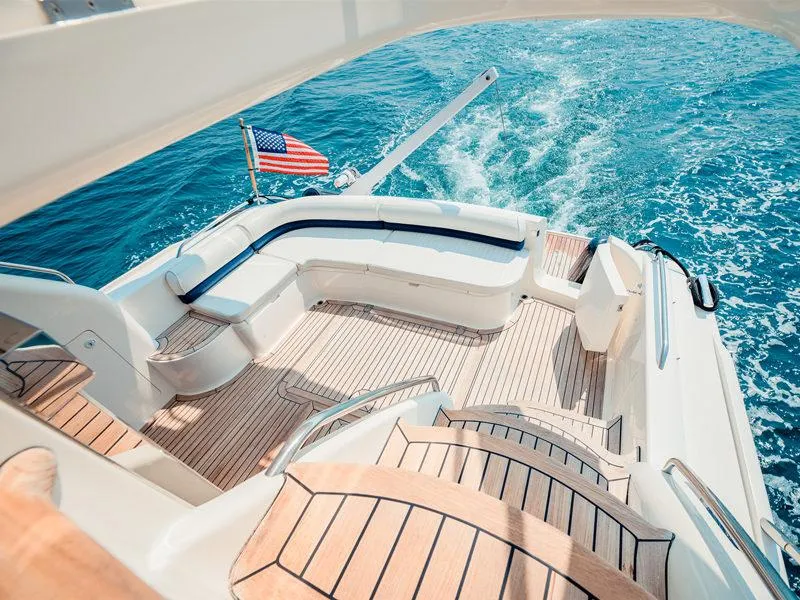 Slide: The Image of Viking 46 Flybridge Sport Cruiser 2000, elegant deck view, American flag, cruising on blue ocean waters. - 4