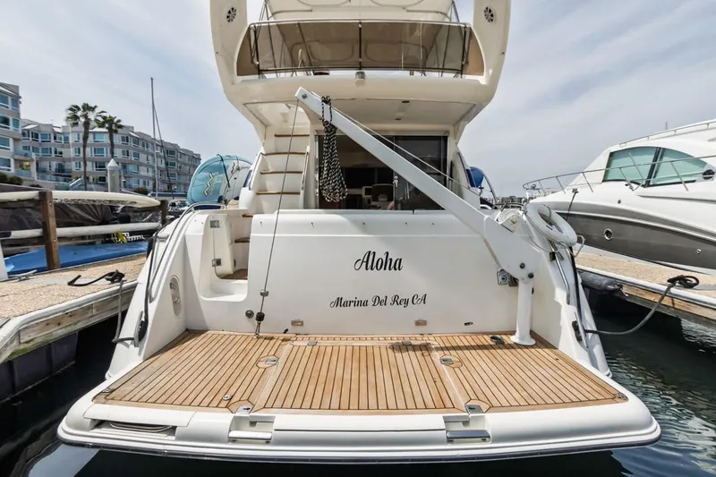 Slide: The Image of 2000 Viking 46 Flybridge Sport Cruiser docked, featuring teak swim platform and "Aloha" name. - 7