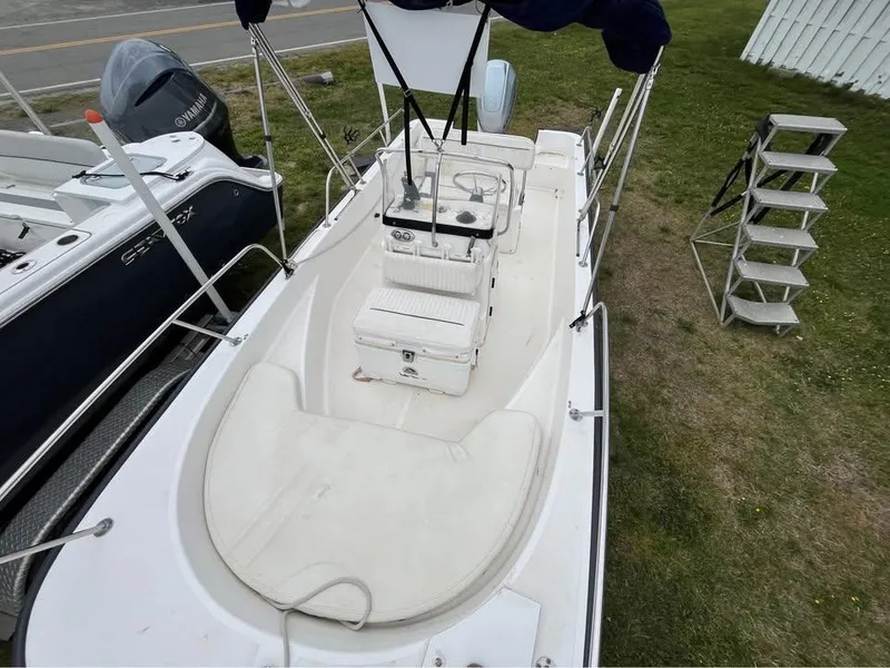 Slide: The Image of 2003 Boston Whaler 170 Montauk boat, aerial view, parked on grass, with visible console and seating. - 2