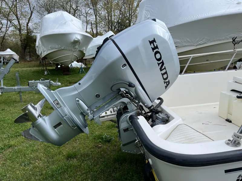 Slide: The Image of 2003 Boston Whaler 170 Montauk with Honda outboard motor, parked on grass. - 7