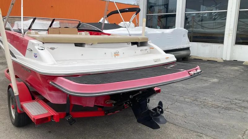 Slide: The Image of 2016 Glastron GT 205 boat with red and white exterior, parked on a trailer. - 2