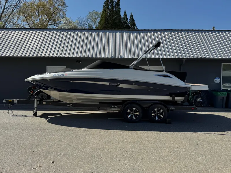 Slide: The Image of 2015 Sea Ray 220 Sundeck boat on trailer, parked outdoors. - 2