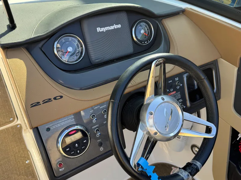 Slide: The Image of 2015 Sea Ray 220 Sundeck dashboard with steering wheel and Raymarine display. - 20