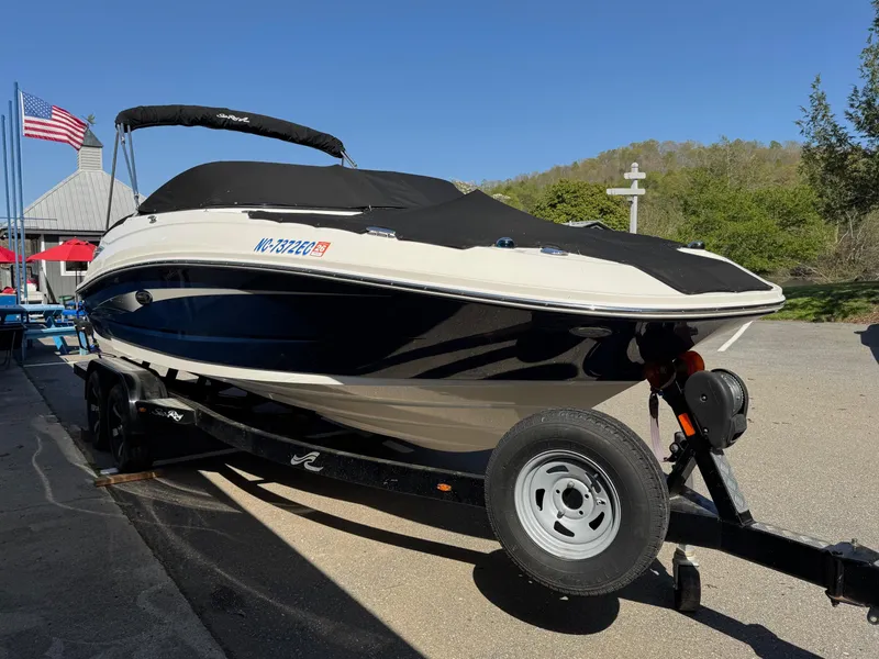Slide: The Image of 2015 Sea Ray 220 Sundeck boat on trailer, parked outdoors under clear blue sky. - 3