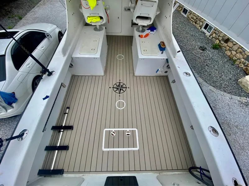 Slide: The Image of 2007 Eastern 27 boat interior with clean deck and seating, parked beside a white car. - 11