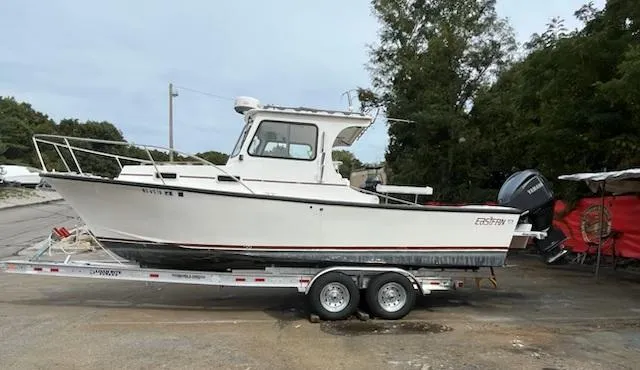 Slide: The Image of 2007 Eastern 27 boat on trailer, parked outdoors, with trees in the background. - 2