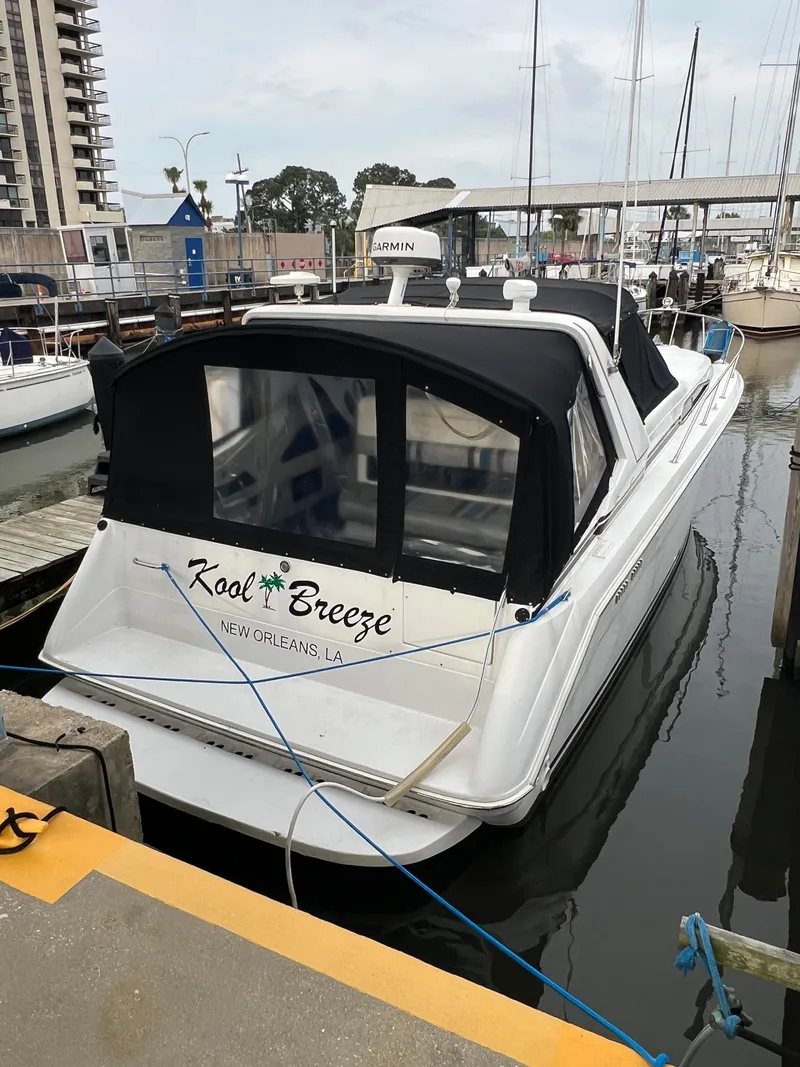 The Image of 1991 Sea Ray 350 Sundancer docked, named "Kool Breeze," with black canopy in marina setting. - 1