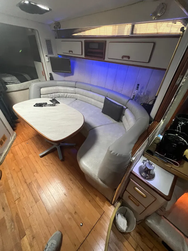 Slide: The Image of 1991 Sea Ray 350 Sundancer interior with curved seating, table, and wood flooring. - 20