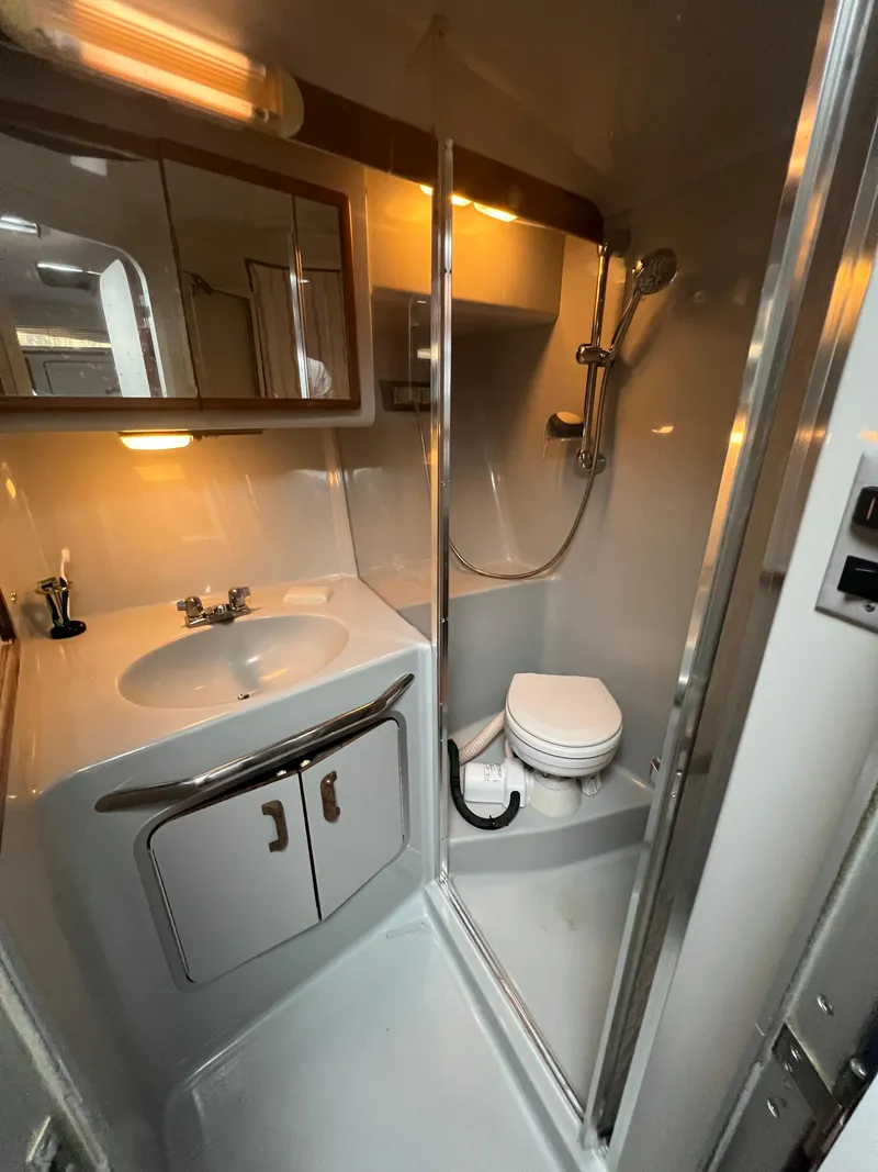 Slide: The Image of 1991 Sea Ray 350 Sundancer bathroom with shower, sink, and toilet in compact design. - 25