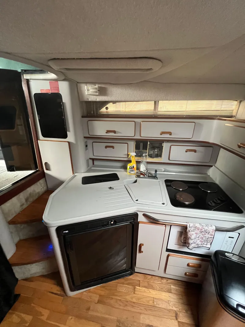 Slide: The Image of 1991 Sea Ray 350 Sundancer interior kitchen with stove, sink, and storage cabinets. - 28