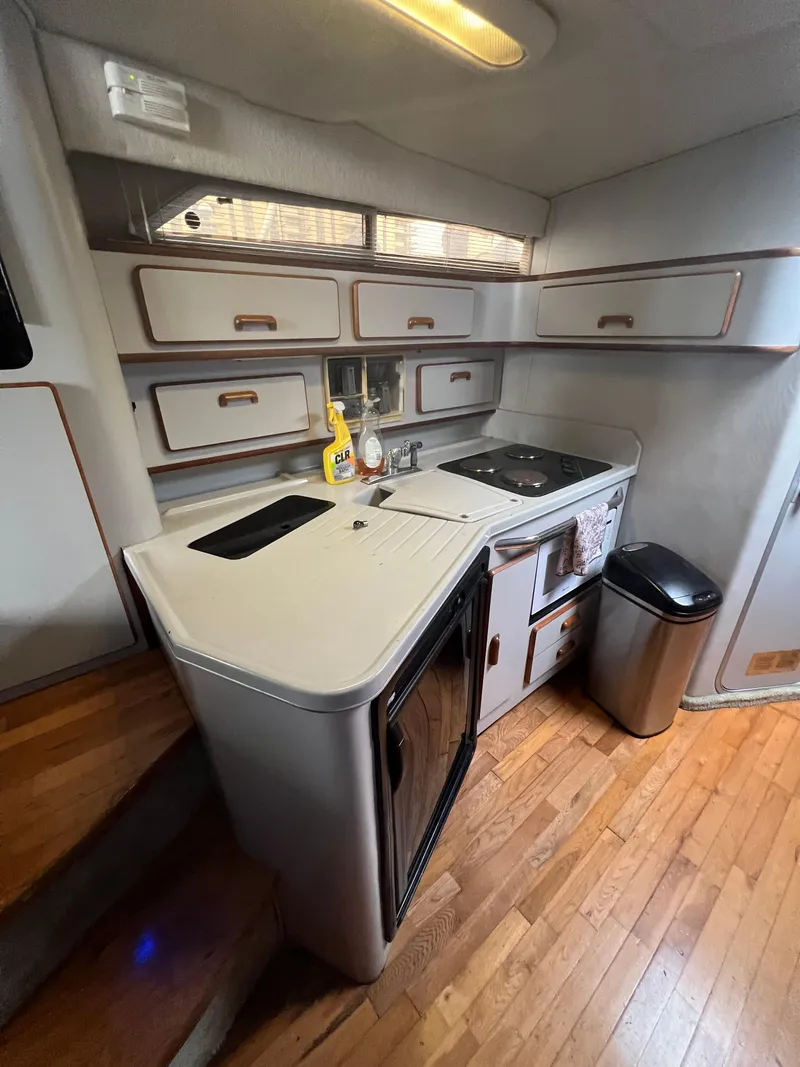 Slide: The Image of 1991 Sea Ray 350 Sundancer kitchen with wooden flooring, compact appliances, and ample storage. - 29