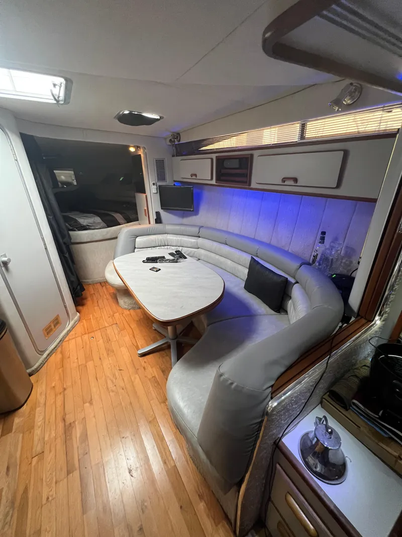 Slide: The Image of 1991 Sea Ray 350 Sundancer interior with curved seating, wooden flooring, and modern amenities. - 30