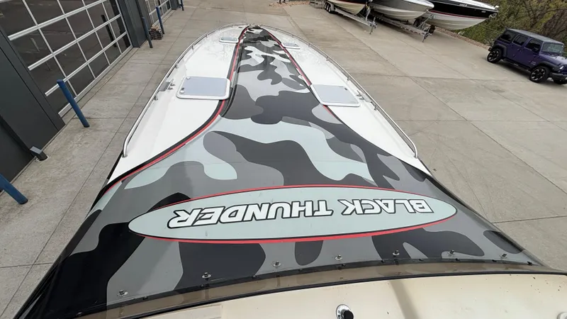 Slide: The Image of 2002 Black Thunder 460 EC boat with camouflage design on deck, parked outdoors. - 38