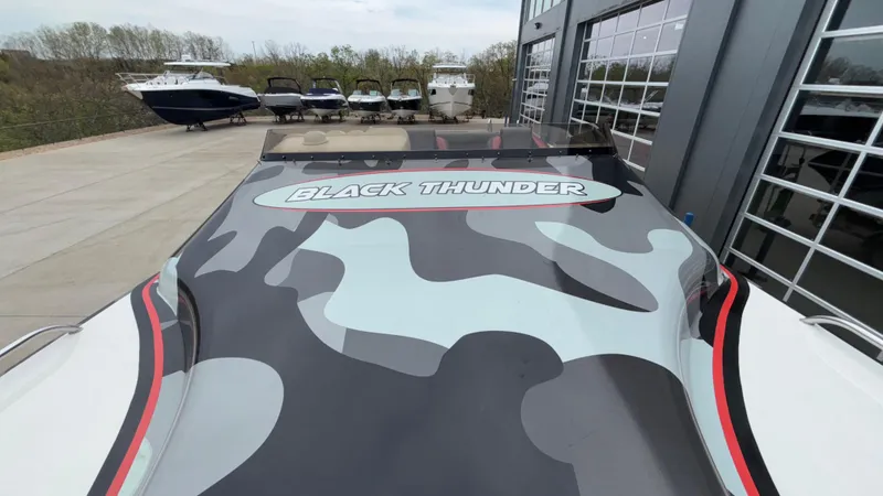 Slide: The Image of 2002 Black Thunder 460 EC boat with camouflage design, docked near other boats. - 39