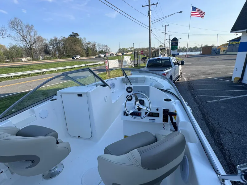 Slide: The Image of 2023 Key West 203 DFS boat interior with steering wheel, parked near road and American flag. - 19