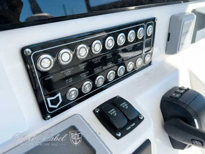 Slide: The Image of Control panel of 2025 Sea Fox 288 Commander boat with labeled switches and trim tabs. - 14