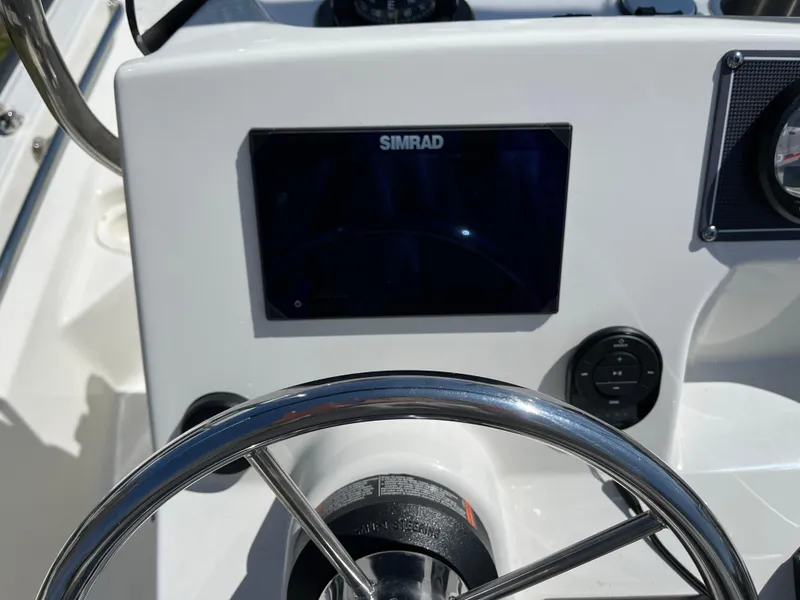 Slide: The Image of 2024 Boston Whaler 150 Montauk dashboard with Simrad display and steering wheel. - 10