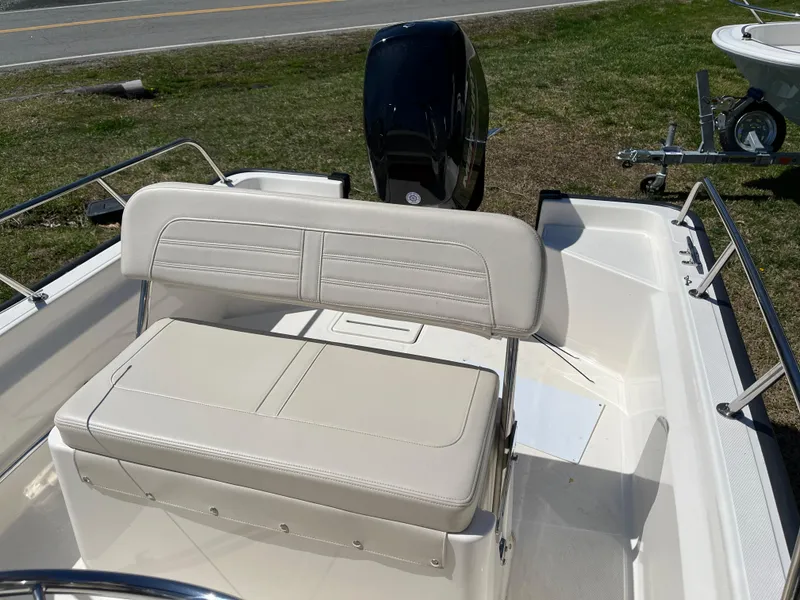 Slide: The Image of 2024 Boston Whaler 150 Montauk boat interior with cushioned seating and motor. - 13