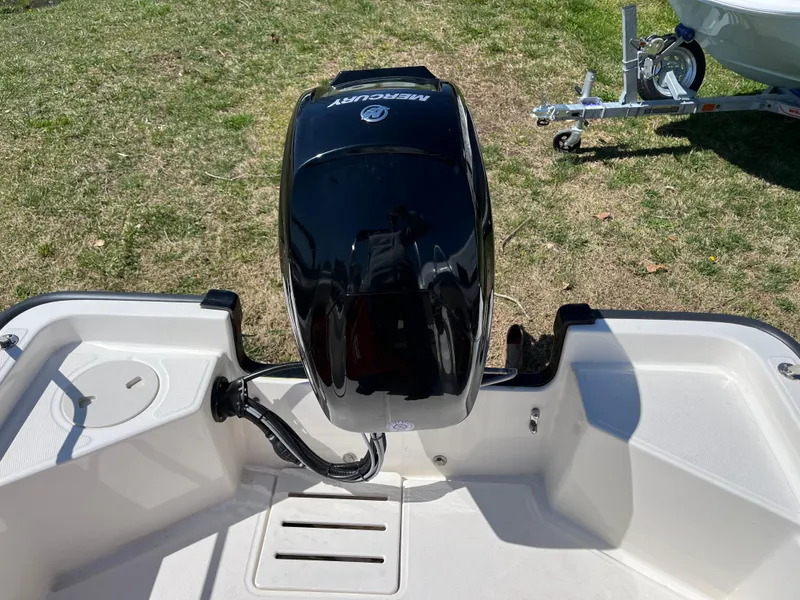 Slide: The Image of 2024 Boston Whaler 150 Montauk boat with Mercury outboard motor, displayed on grass. - 15