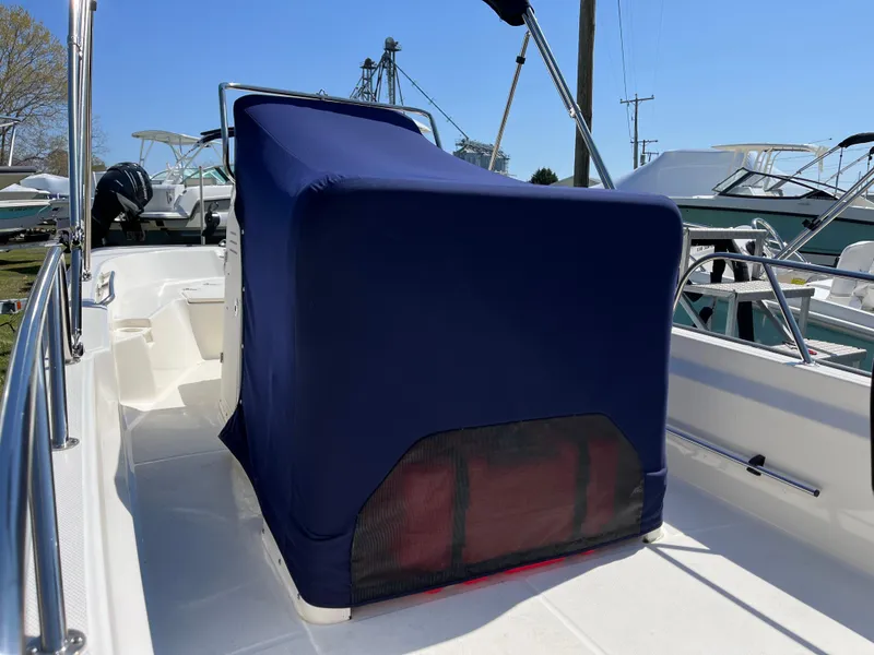 Slide: The Image of 2024 Boston Whaler 150 Montauk boat with blue cover, docked in marina. - 18