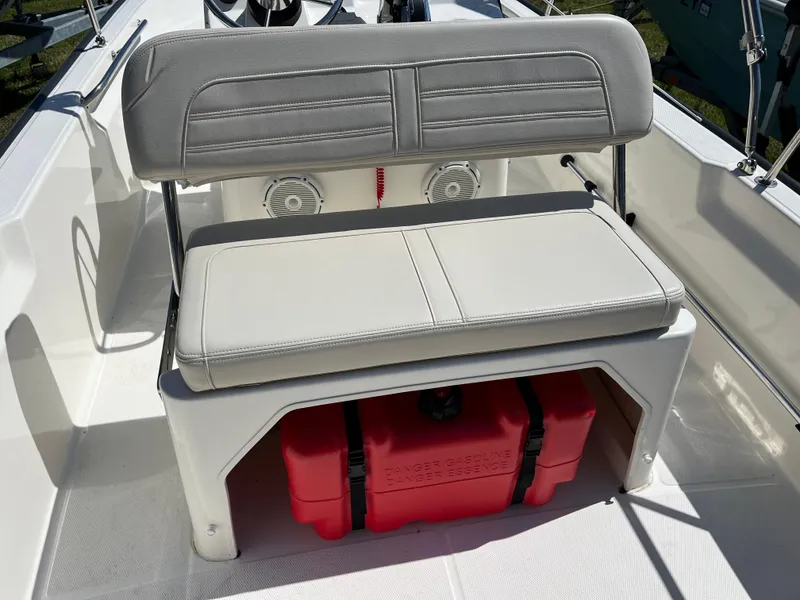 Slide: The Image of 2024 Boston Whaler 150 Montauk boat seat with storage and red container underneath. - 5