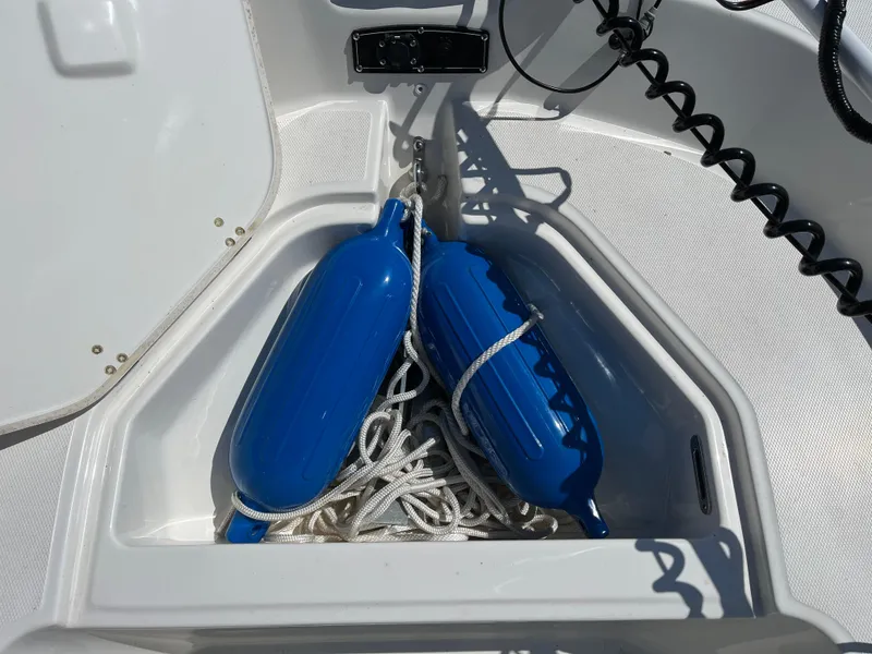Slide: The Image of 2024 Boston Whaler 150 Montauk storage compartment with blue fenders and white ropes. - 8