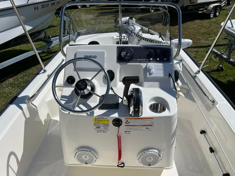 Slide: The Image of 2024 Boston Whaler 150 Montauk boat dashboard with steering wheel and controls. - 9