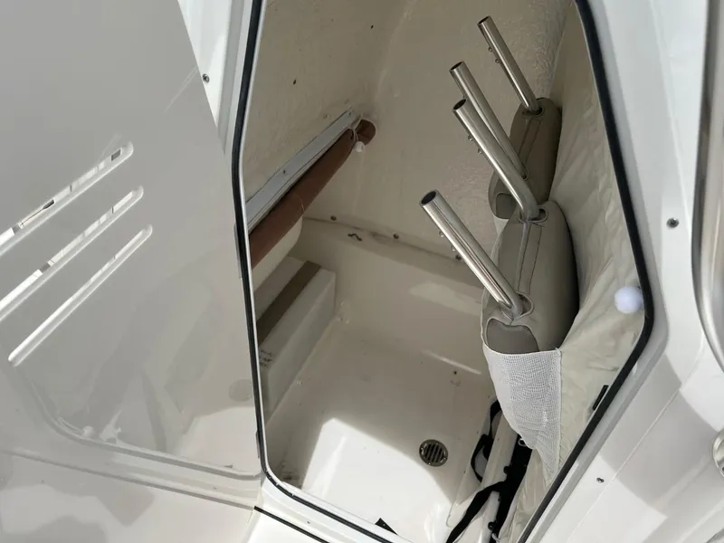 Slide: The Image of 2024 Key West 239 FS boat storage compartment with rod holders and white interior. - 22
