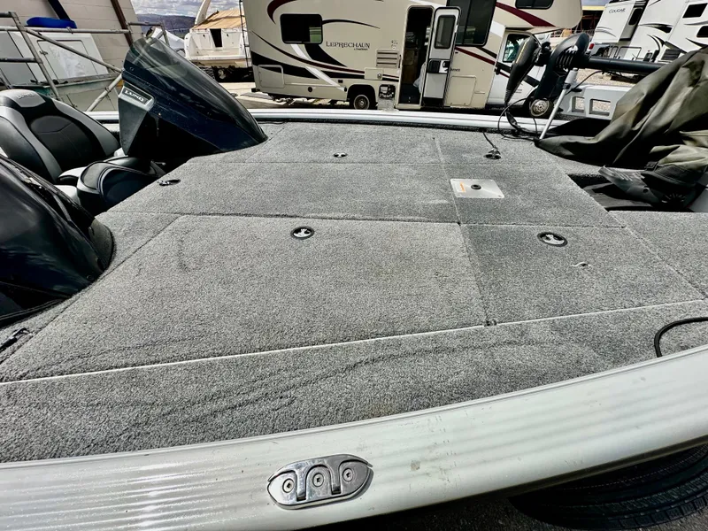 Slide: The Image of 2018 Lund 1875 Pro-V Bass boat deck with carpeted surface and storage compartments. - 10