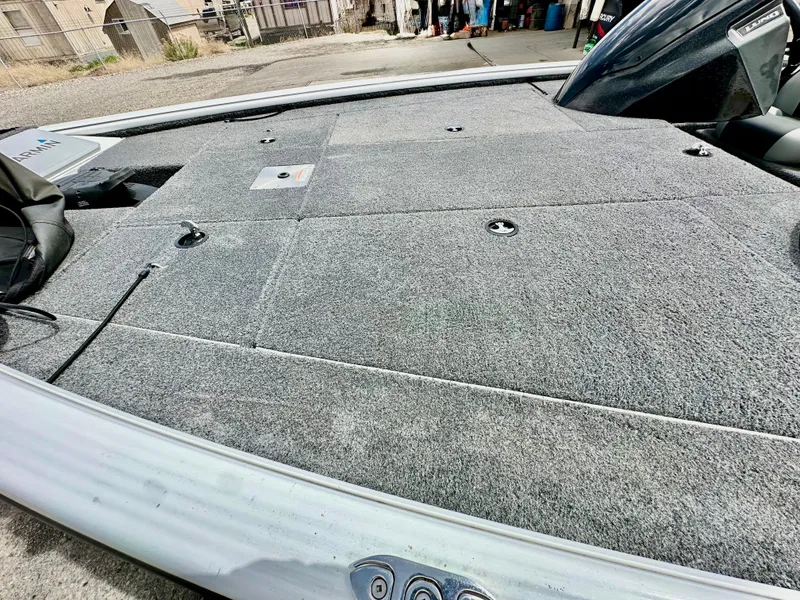 Slide: The Image of 2018 Lund 1875 Pro-V Bass boat deck with gray carpet and storage compartments. - 12