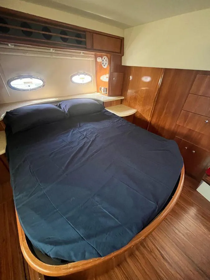 Slide: The Image of 2000 Carver 396 Motor Yacht bedroom with wood paneling and porthole windows. - 24