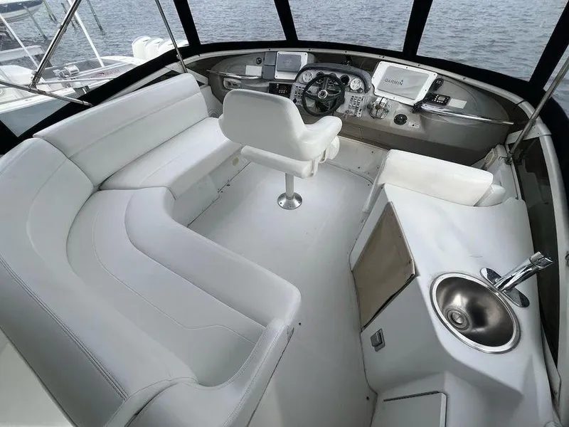 Slide: The Image of 2000 Carver 396 Motor Yacht cockpit with white seating, steering console, and sink. - 6
