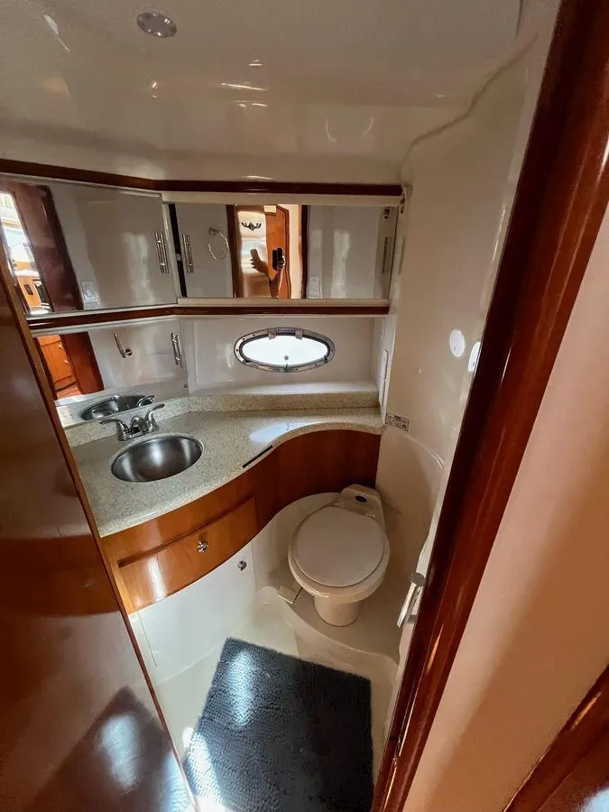 Slide: The Image of 2000 Carver 396 Motor Yacht bathroom with sink, toilet, and porthole window. - 26
