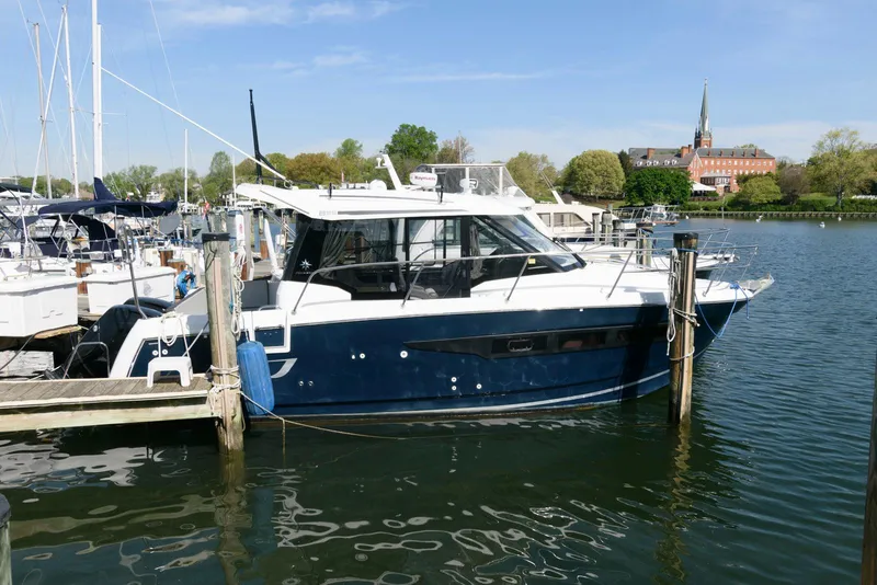 Slide: The Image of 2019 Jeanneau NC 895 boat docked in a marina with scenic background. - 0